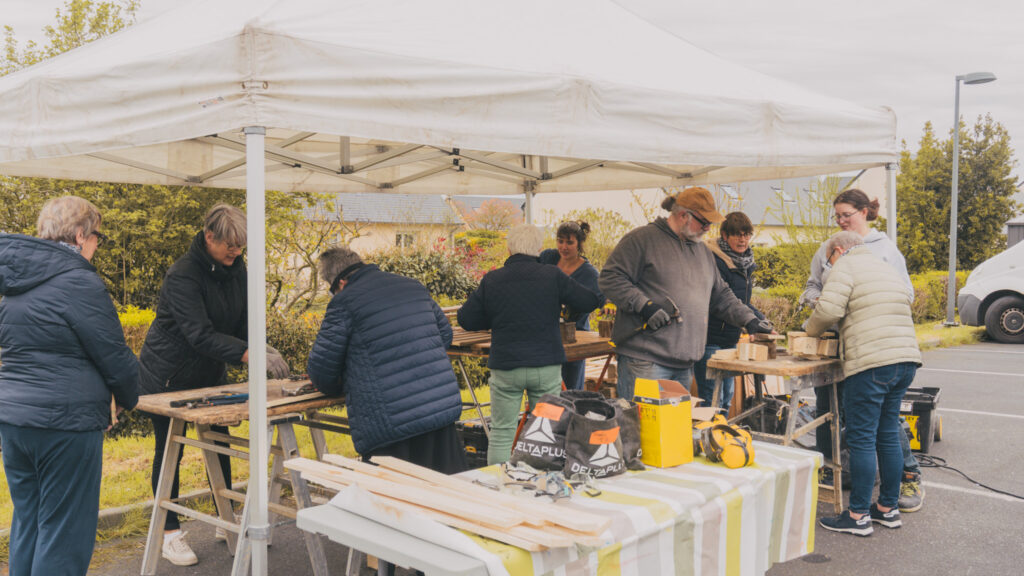 Participants bricolant un nichoir en bois de récupération pendant les Cafés des Astucieux